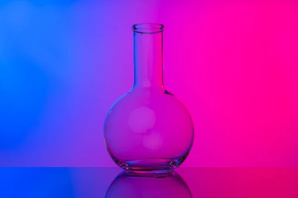 Хімічний скляний посуд крупним планом на неоновому рожево-фіолетовому фоні — стокове фото