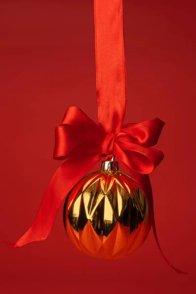Bela bugiganga de Natal pendurado em fita de cetim vermelho contra fundo vermelho — Fotografia de Stock