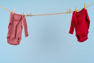 Bebek kıyafetleri mavi arka planda çamaşır ipine takılmış.
