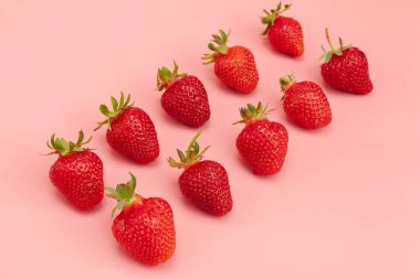 Pembe arka planda çilekler. Taze organik gıda konsepti