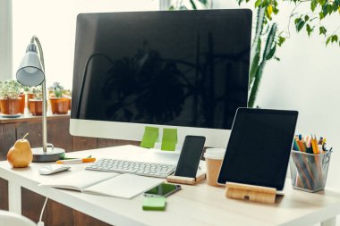 Ofis ya da ev işi. Ofis masasında malzemelerle siyah ekranlı bilgisayar monitörü