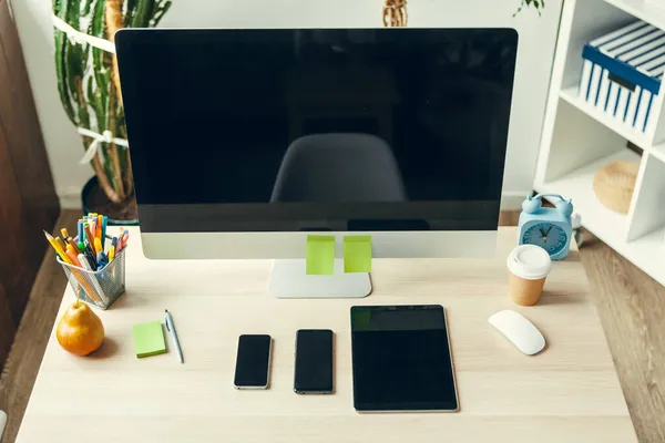 Офис или домашнее рабочее место. Компьютерный монитор с черным экраном на рабочем столе с принадлежностями — стоковое фото
