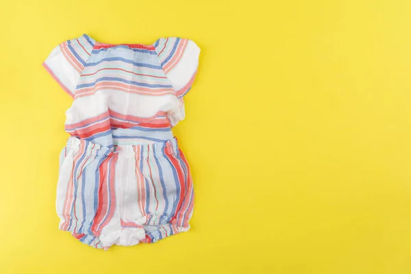 赤ちゃんの女の子の服の上からの眺め黄色の背景 — ストック写真