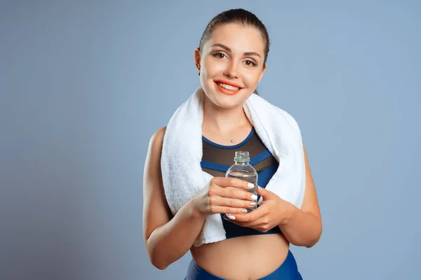 Passform sportig kvinna som håller mineralvatten flaska i handen — Stockfoto