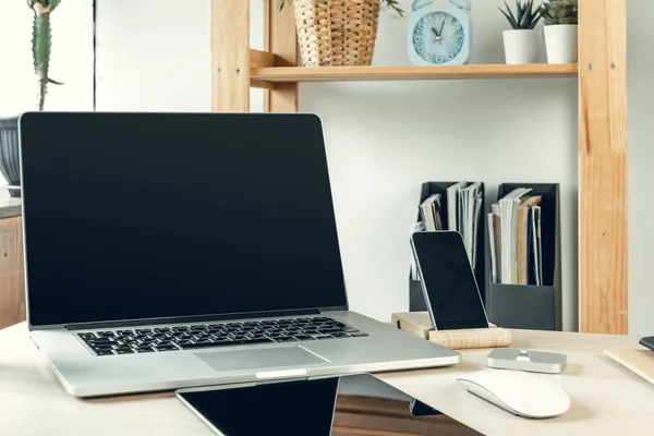 Laptop i ett ljust rum på arbetsbord med kontorsmaterial — Stockfoto