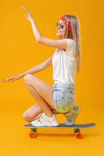 Pretty happy woman casually dressed sits on her skateboard — Stock Photo, Image