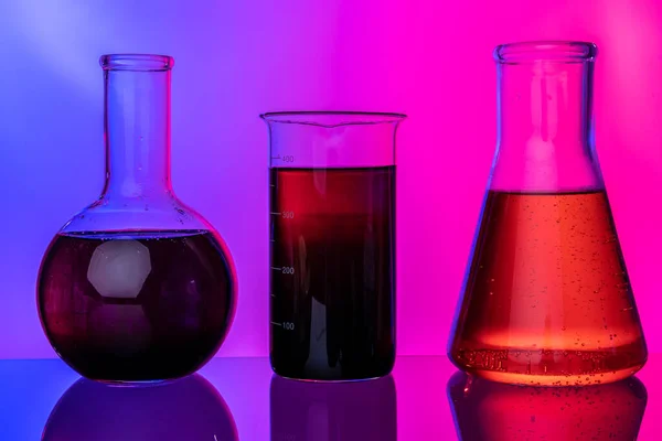 Laboratory glass tubes with chemicals on bright pink background — Stock Photo, Image