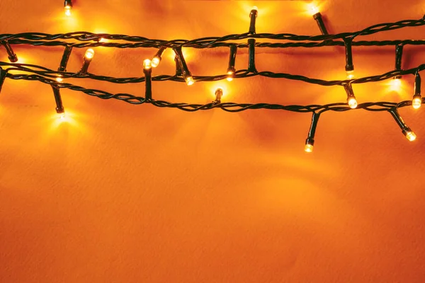 Fundo laranja com luzes iluminadas de guirlanda — Fotografia de Stock