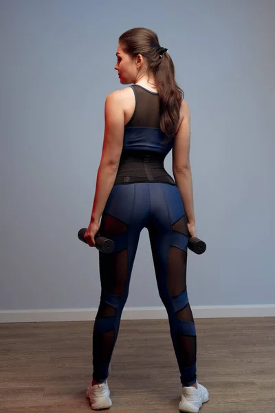 Portrét fitness modelu s činkami na šedém pozadí — Stock fotografie