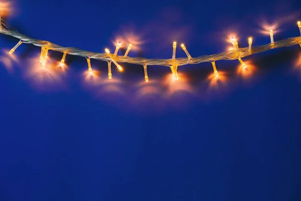 Fundo azul com luzes iluminadas de guirlanda — Fotografia de Stock