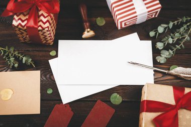 Noel eşyalarıyla süslenmiş, eski ahşap arka planda tüy olan boş bir mektup.