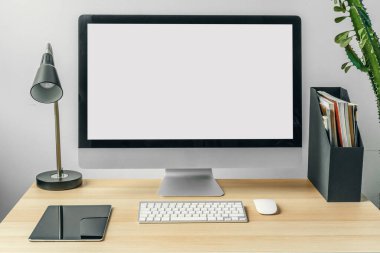 Ofis masasında malzemelerle birlikte beyaz ekranlı bilgisayar monitörü