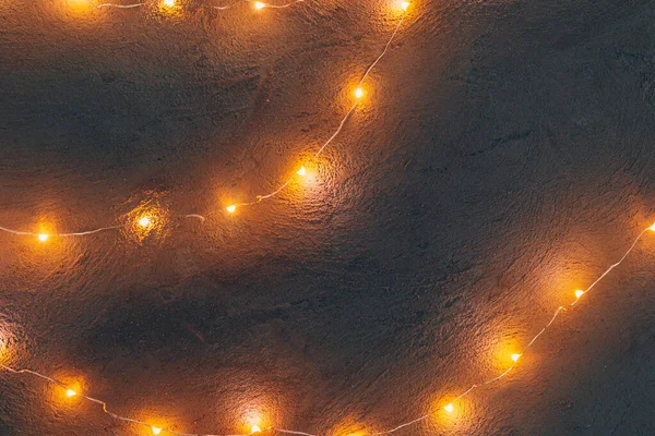 Guirnalda iluminada de luz cálida de cerca sobre fondo oscuro —  Fotos de Stock