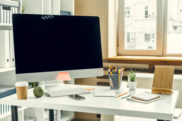 Oficina o espacio de trabajo en casa. Monitor de ordenador con pantalla negra en la mesa de oficina con suministros — Foto de Stock