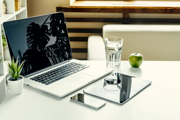 Öppen laptop på bord nära soffa, heminredning. Frilansande arbetsplatskoncept — Stockfoto