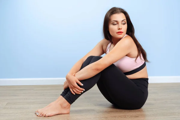 Fit woman in sportswear sitting on the floor in a gym — Stock Photo, Image