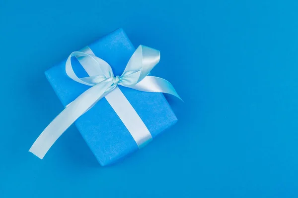 Flat lay de caixa de presente decorado com arco sobre fundo azul — Fotografia de Stock