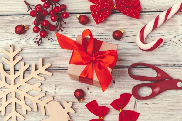 Czerwony prezent świąteczny z dekoracjami na drewnianym tle — Zdjęcie stockowe