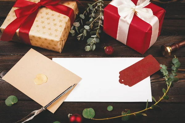 Noel eşyalarıyla süslenmiş, eski ahşap arka planda tüy olan boş bir mektup. — Stok fotoğraf