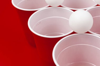 Bardaklar ve plastik top kırmızı arka planda. Bira pong oyunu