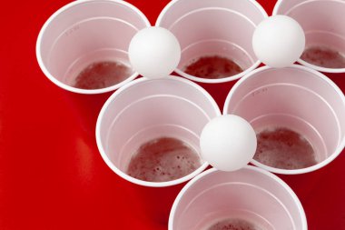 Bardaklar ve plastik top kırmızı arka planda. Bira pong oyunu