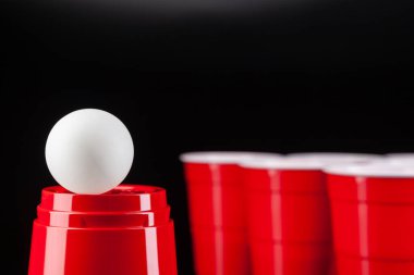 Bira oyunu için kırmızı plastik bardaklar ve top.