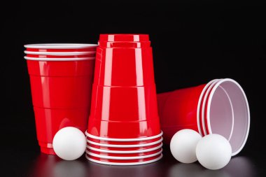 Bira oyunu için kırmızı plastik bardaklar ve top.