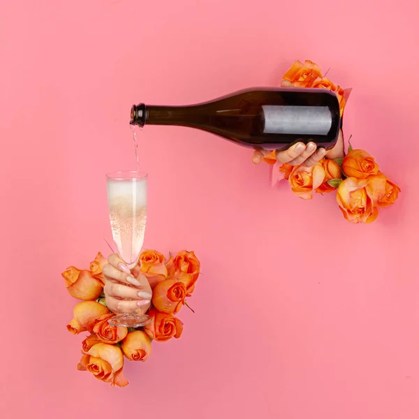 Manikürlü kadın eli, güllerle süslenmiş yırtık bir kağıtta bir bardağa şampanya dolduruyor. — Stok fotoğraf
