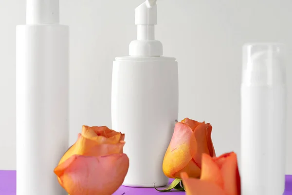 Cosmetische flessen met rozenblaadjes, kopieerruimte — Stockfoto