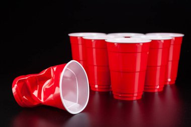 Bira oyunu için kırmızı plastik bardaklar ve top.