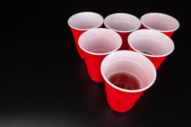 Bira oyunu için kırmızı plastik bardaklar ve top.