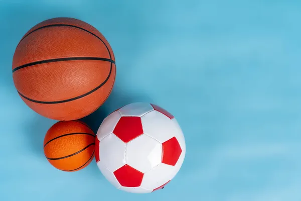 Balles de basket-ball et de football sur fond bleu — Photo