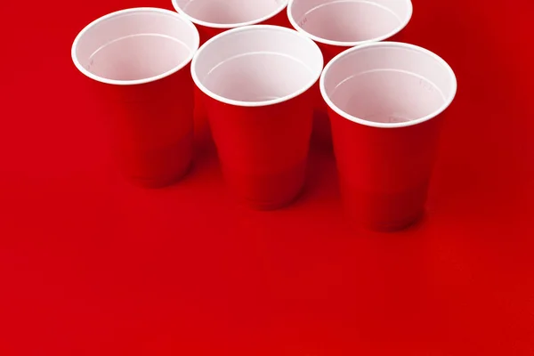 Tazze e palla di plastica su sfondo rosso. Birra pong gioco — Foto Stock