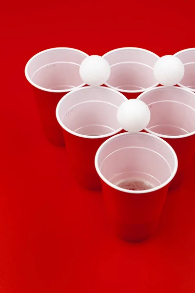 빨간 배경에는 컵과 플라스틱 공이 있습니다. 맥주 퐁 경기 — 스톡 사진