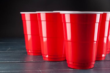 Kırmızı bardaklı ahşap masa ve bira pong topu.