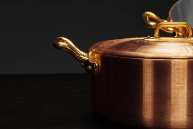 Koyu arkaplan üzerinde yeni bakır pişirme takımı