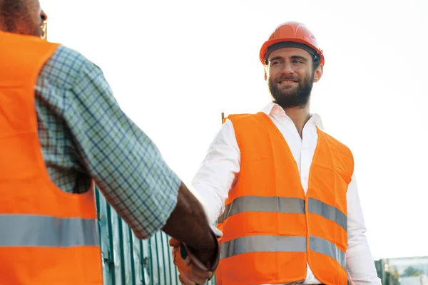 Close up foto de dois homens construtores em workwear apertando as mãos — Fotografia de Stock