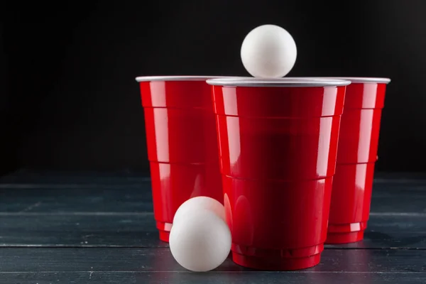 Wooden table with red cups and ball for beer pong — Stock Photo, Image
