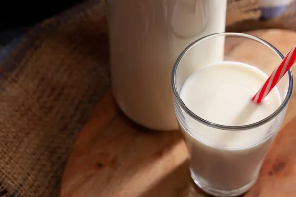 Glas en fles melk op houten plank close-up — Stockfoto