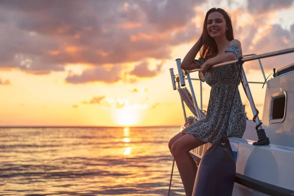 Junge attraktive Frau sitzt auf dem Deck der Jacht und genießt den Sonnenuntergang — Stockfoto