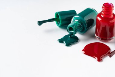 Beyaz arka planda şişelerden oje döküldü.