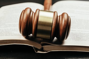 Açık kitabın arka planında kahverengi tahta yargıç tokmağı