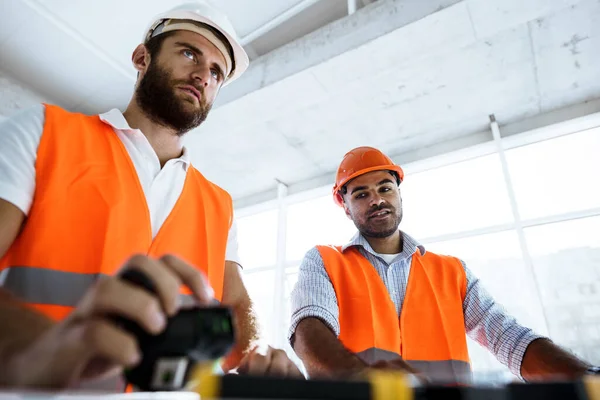 Porträtt av två unga byggingenjörer i hatt på byggarbetsplatsen — Stockfoto