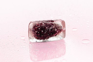 Donmuş böğürtlenler pembe üzerinde buz küpleri