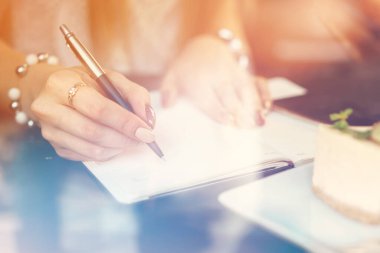 Bir kafede otururken not alan bir kadın.