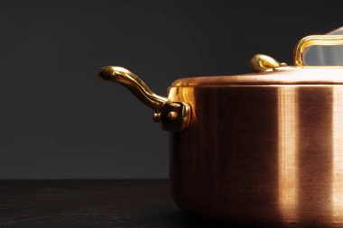 Koyu arkaplan üzerinde yeni bakır pişirme takımı