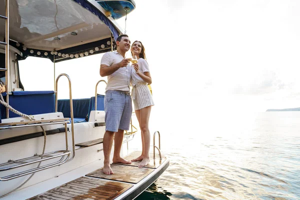 Jeune couple amoureux assis sur le pont du yacht et buvant du vin — Photo