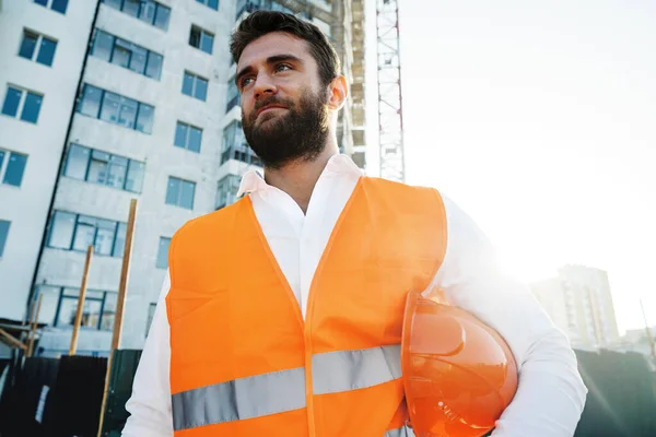 Byggare med hatt och skyddsväst stående på en kommersiell byggarbetsplats — Stockfoto