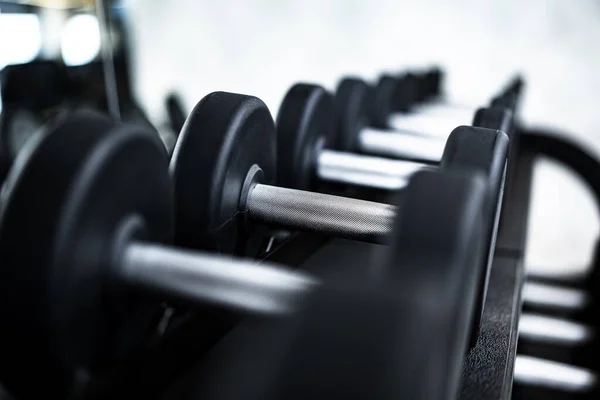 Primer plano de nuevas mancuernas en un estante en un gimnasio — Foto de Stock