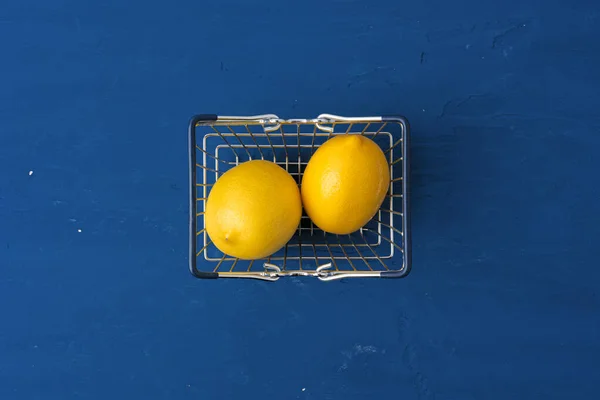 전형적 인 파란색 배경의 쇼핑 카트에 있는 레몬, 맨 위에 보이는 것 — 스톡 사진